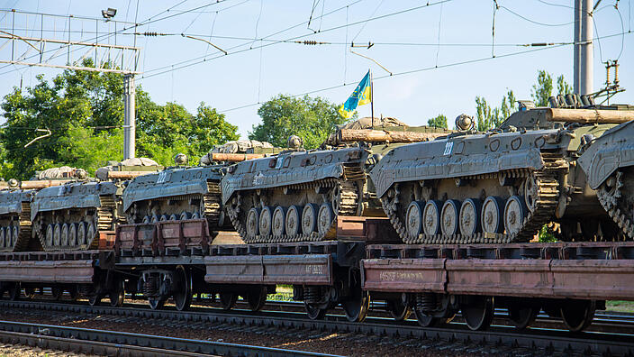 Cargo train carrying military tanks on railway flat wagons