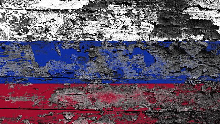 Painted colors of the Russian flag peeling off a wooden wall
