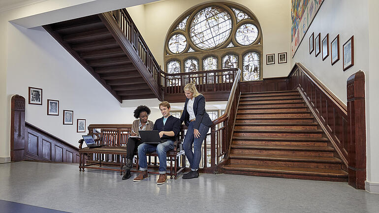 Personen sitzen auf einer Bank im Treppenhaus des IfW Kiel